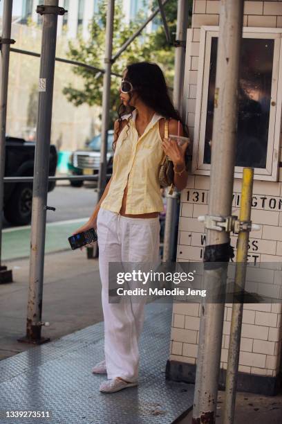 Guest in yellow sleeveless cotton button-up top and white linen pants Maryam Nassir Zadeh show on September 08, 2021 in New York City.