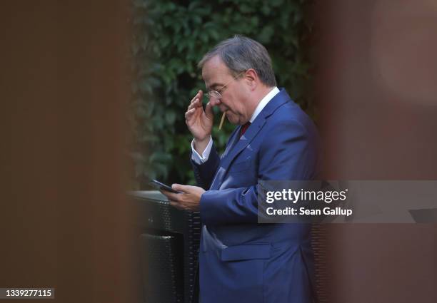 Armin Laschet, leader of the German Christian Democrats and CDU/CSU chancellor candidate, smokes a cigarette as he prepares to speak at a gathering...