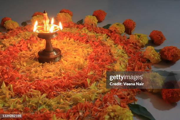 pookalam with lit brass lamp in the middle/floral rangoli/floral pattern/onam festival/kerala - onam foto e immagini stock