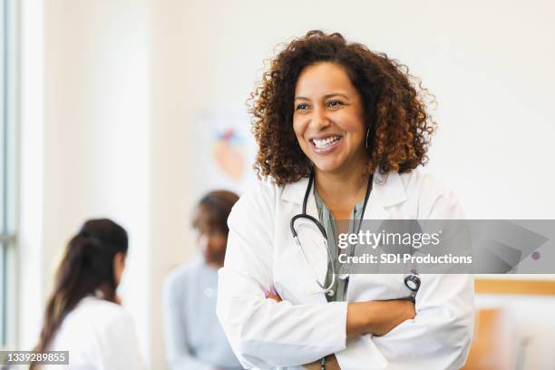 mid adult female doctor smiles for camera - female doctor stock pictures, royalty-free photos & images