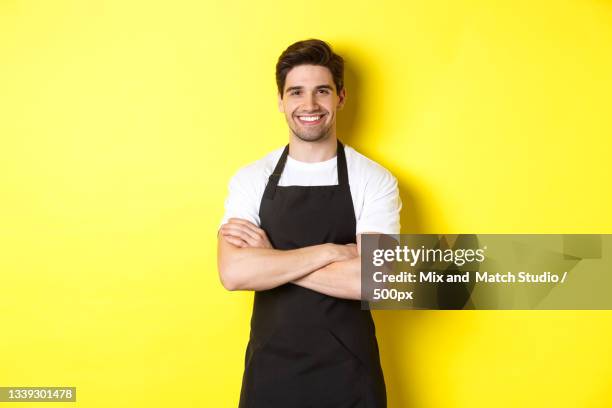 portrait of smiling man standing on yellow background - avental imagens e fotografias de stock