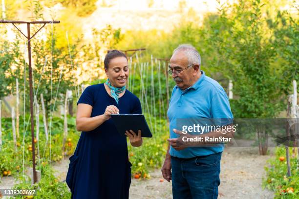 business woman and farmer reading documents in field - farmers insurance stock pictures, royalty-free photos & images