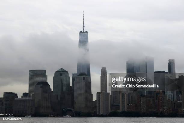 Wrapped in rain clouds, One World Trade Center stands high on the Lower Manhattan skyline from Liberty State Park on September 09, 2021 in Jersey...