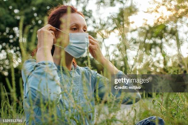 woman sitting outdoors and suffering from pollen allergy - ambrosia stock pictures, royalty-free photos & images