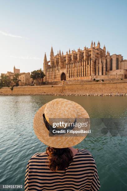 rear view of a woman with a straw hat while she's admiring the cathedral de santa maría de palma de mallorca at sunset - palma de mallorca bildbanksfoton och bilder