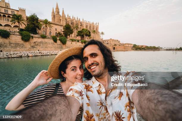 a couple is taking a selfie near the cathedral de palma de mallorca at sunset - palma majorca stock pictures, royalty-free photos & images