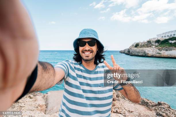 ein mann macht ein selfie in der nähe des meeres - sonnenhut stock-fotos und bilder