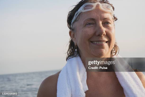 portrait of a mature caucasian woman after swimming in the ocean/sea - morning swim stockfoto's en -beelden