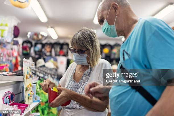 senior couple paying in the shop. - dolours price stock pictures, royalty-free photos & images