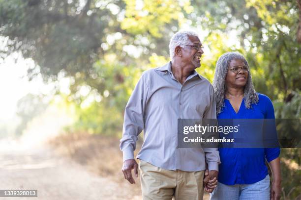 senior black couple walking on a nature trail - seniors walking stock pictures, royalty-free photos & images