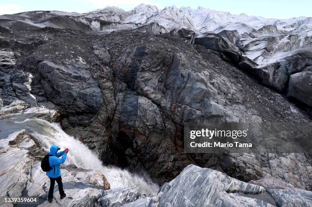 Tourist photographs near meltwater running past the retreating Russell Glacier on September 09, 2021 near Kangerlussuaq, Greenland. 2021 will mark...