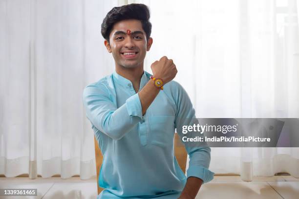 a happy teenager showing rakhi in front of camera - raksha bandhan stock pictures, royalty-free photos & images