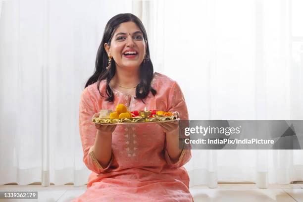 a happy young woman sitting while holding traditional raksha bandhan thali - rakhi ストックフォトと画像