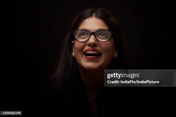 a young woman wearing specs looking above and laughing - exhilaration stock pictures, royalty-free photos & images