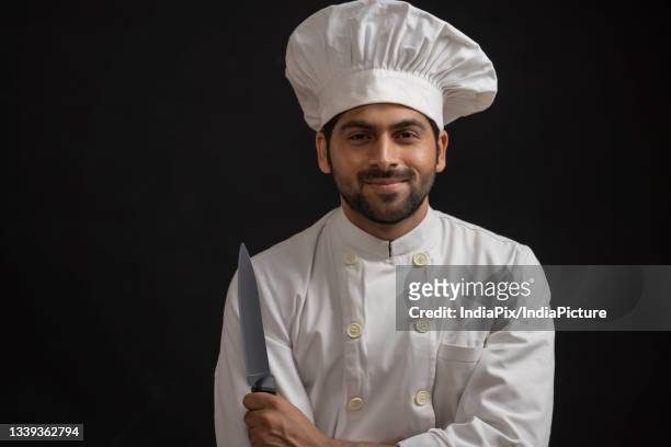 portrait of a professional chef happily posing in front of camera - chef coat stock pictures, royalty-free photos & images