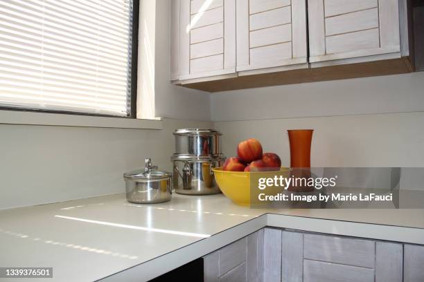 kitchen counter with cookware and bowl of peaches - laminiertes plastik stock-fotos und bilder