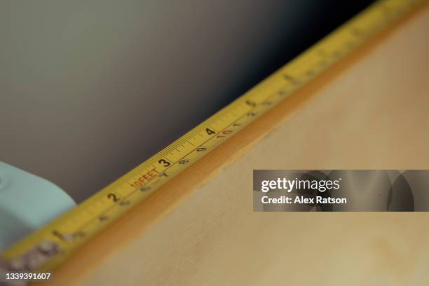 close up of a tape measure running across the length of board - inch stock pictures, royalty-free photos & images