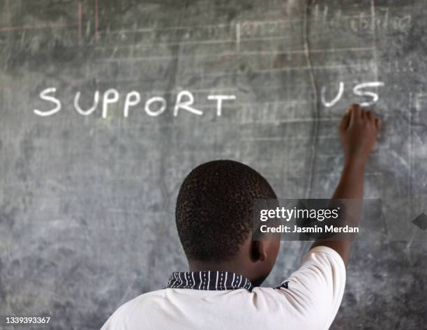 african poor child writing: support us - orphan boy stock pictures, royalty-free photos & images