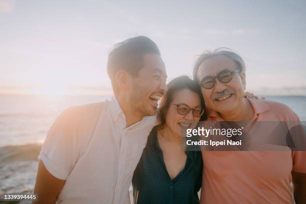 senior father and adult children having fun on beach at sunset - asian smiling father son stock pictures, royalty-free photos & images