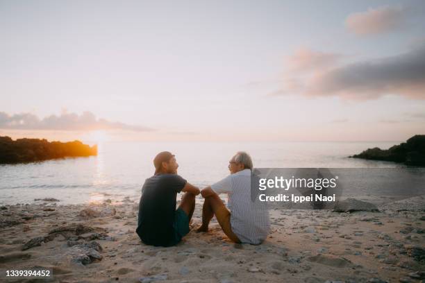 senior father and adult son having a good time on beach at sunset - vivere semplicemente foto e immagini stock