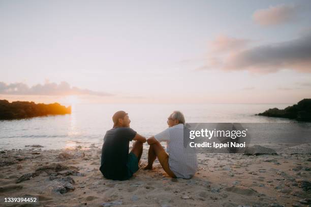 senior father and adult son having a good time on beach at sunset - 2 people back asian imagens e fotografias de stock