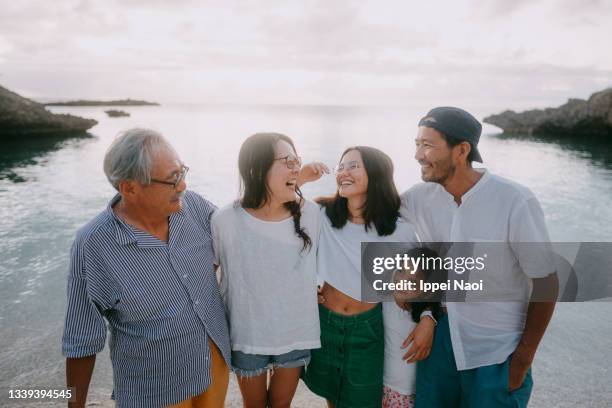 cheerful family having a good time on beach at dusk - asian family stockfoto's en -beelden