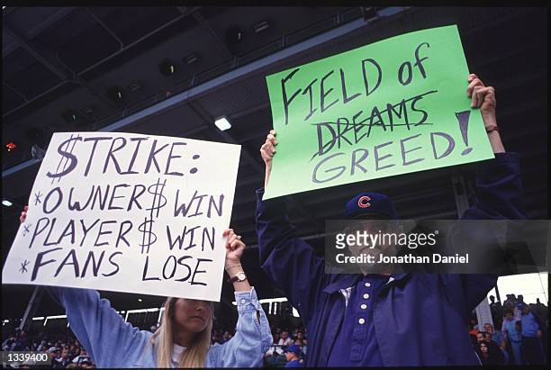 Fans hold up signs in protest of the baseball strike during a game between the San Francisco Giants and the Chicago Cubs at Wrigley Field in Chicago,...