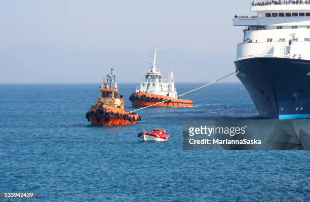 tugboats towing a ferry into a harbor - pulling stockfoto's en -beelden