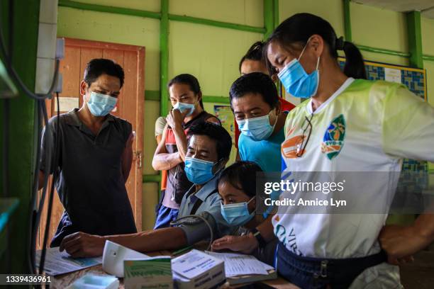 Villagers gather as they check a man's blood pressure ahead of his CanSino vaccination at Kampung Longkogungan on September 10, 2021 in Kota...