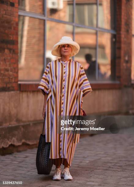 Maria Gieseke wearing a colorful maxidress, a beige hat and sneakers on September 08, 2021 in Berlin, Germany.