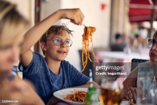familie beim mittagessen im straßenrestaurant - spaghetti stock-fotos und bilder