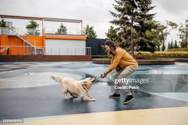 homme jouant à des jeux de traction avec son chien - jouet pour chien photos et images de collection