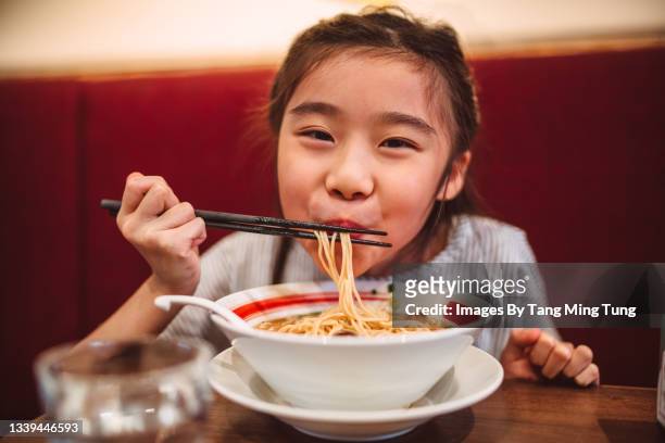 lovely cheerful girl smiling joyfully at camera while enjoying noodle soup in restaurant - bowl of ramen stock pictures, royalty-free photos & images