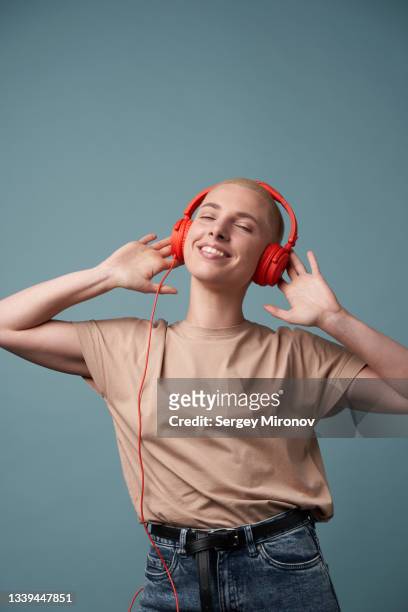 woman dancing with red headphones against blue wall - women dancing on music cutout photos et images de collection