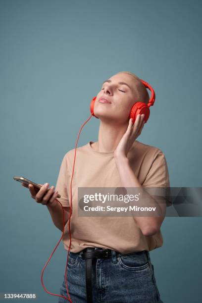 woman dancing with red headphones against blue wall - women dancing on music cutout photos et images de collection