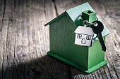 House key on a house shaped key chain with green wooden home environmentally friendly property