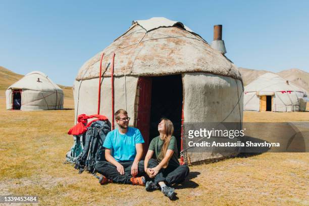 jovem sorridente mulher e homem mochileiros encontra manhã nas montanhas do acampamento yurt no quirguistão - pessoas nômades - fotografias e filmes do acervo