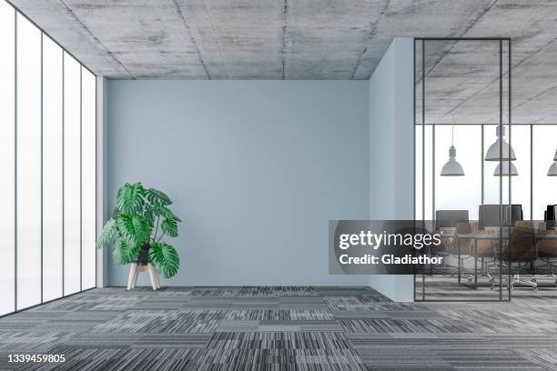 large office interior: a lounge corner with a potted plant, copy space and wordesks behind glass door - empty office stockfoto's en -beelden