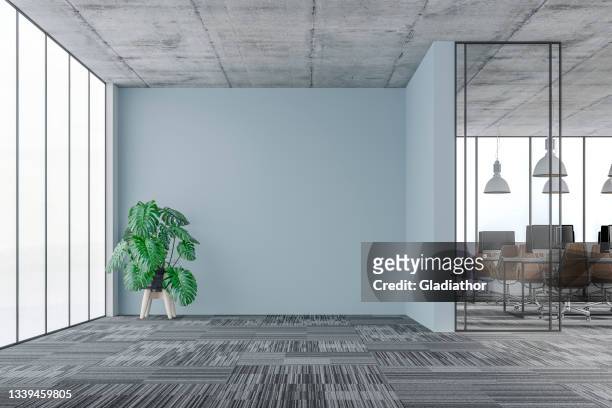 large office interior: a lounge corner with a potted plant, copy space and wordesks behind glass door - carpet stock pictures, royalty-free photos & images