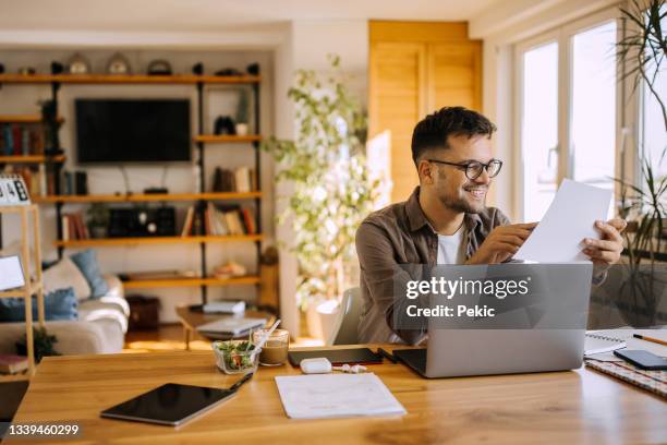 young man working from home - man holding paper stock pictures, royalty-free photos & images