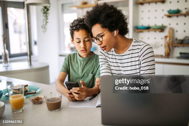 mother working at home, in a company of her teenage son distracting her, using laptop, trying to focus. - two women on phone isolated stock pictures, royalty-free photos & images