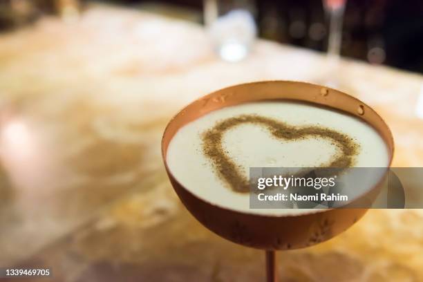 espresso martini cocktail with heart-shaped froth art, served in a trendy bar - espresso martini stock-fotos und bilder