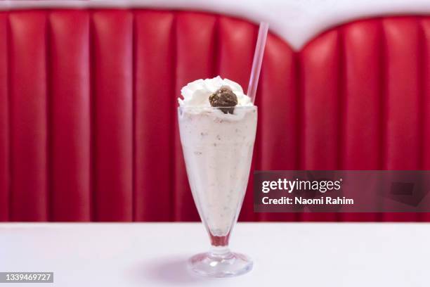 old school milkshake on diner table, in front of retro red booth, 1950s-style - milk shake stock pictures, royalty-free photos & images