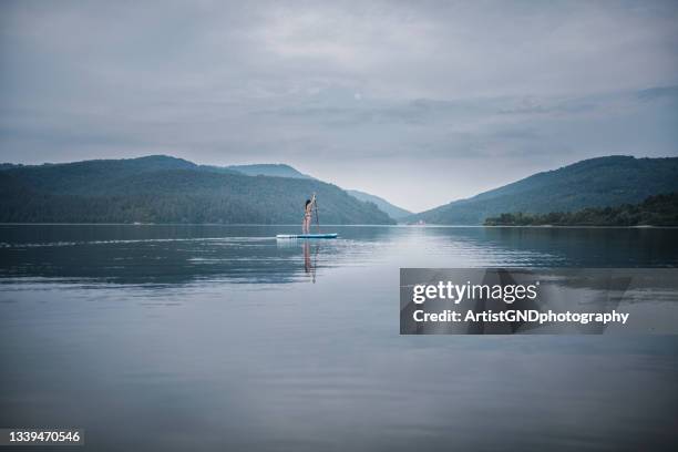 donna riding stand up paddle board nel lago - paddle surf foto e immagini stock