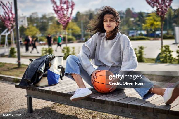 portrait of young woman with curly hair holding basketball - tossing hair facing camera woman outdoors stock pictures, royalty-free photos & images