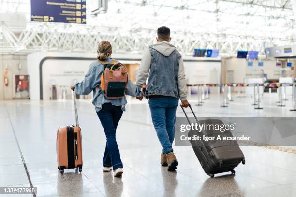 paar am flughafen zu fuß zum einsteigen - airport couple stock-fotos und bilder