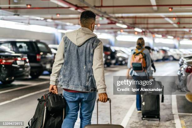 passagiere, die taschen auf dem flughafenparkplatz tragen - airport parking stock-fotos und bilder