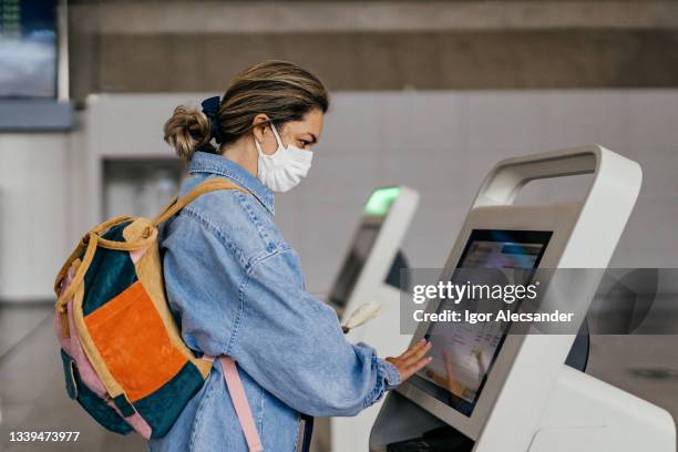 frau mit maske beim self-service-check-in. - selbstbedienung stock-fotos und bilder