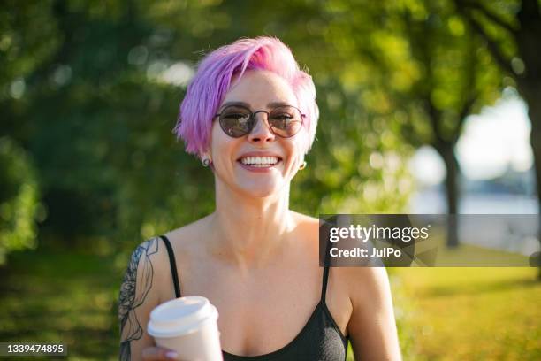 young adult woman walking in park with coffee - disposable cup stock pictures, royalty-free photos & images