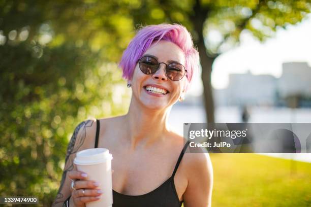 young adult woman walking in park with coffee - disposable cup stock pictures, royalty-free photos & images